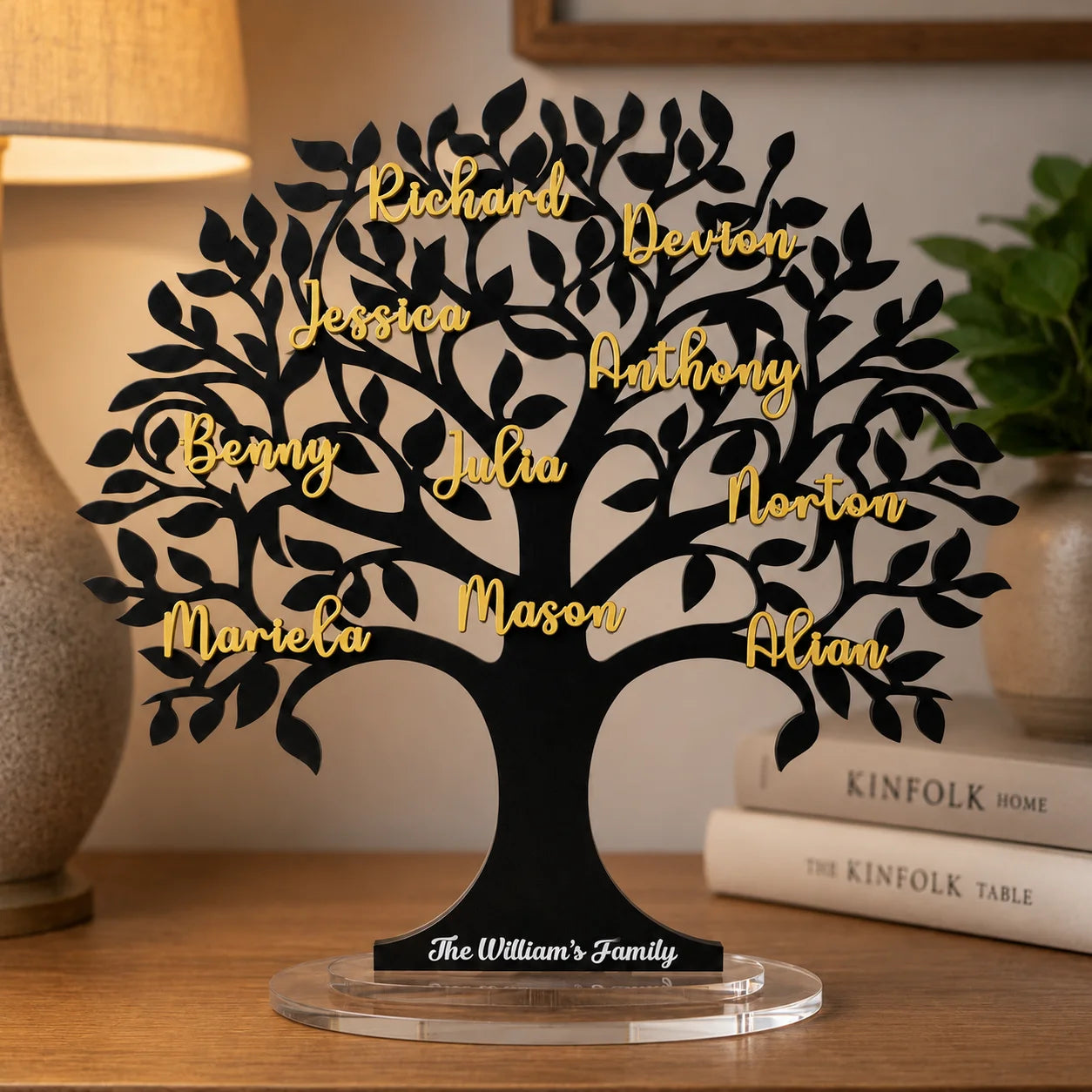 Decorative family tree sculpture with names on a table beside a lamp and books
