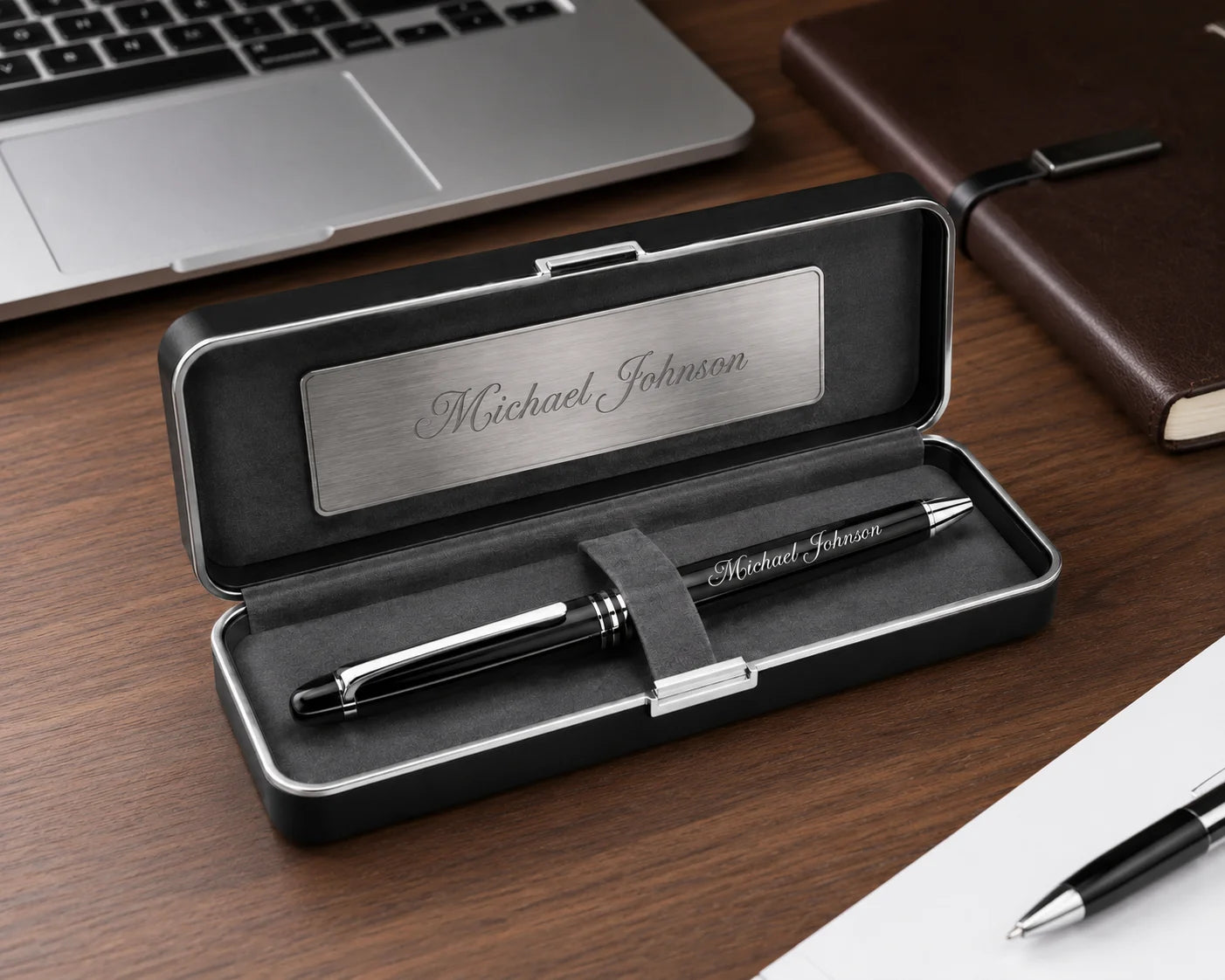Personalized pen set in an open case on a desk next to a laptop and notebook