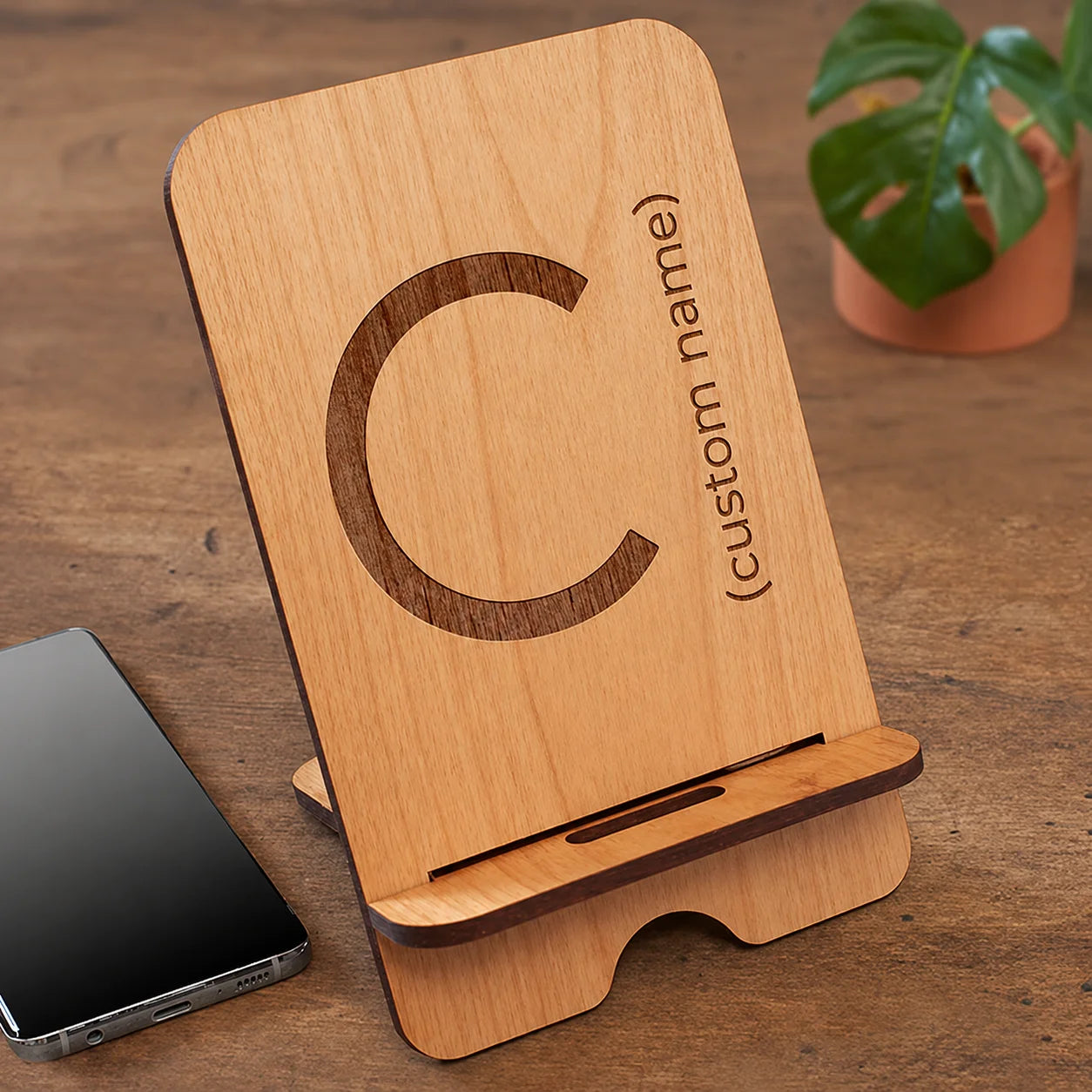 Wooden phone stand with custom name engraving and large letter C on table